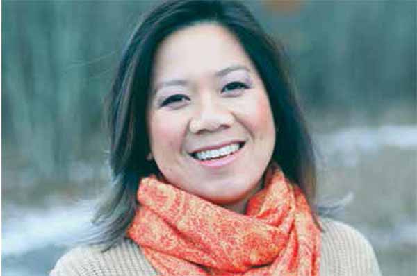 Andrea Wang smiles in an orange scarf.