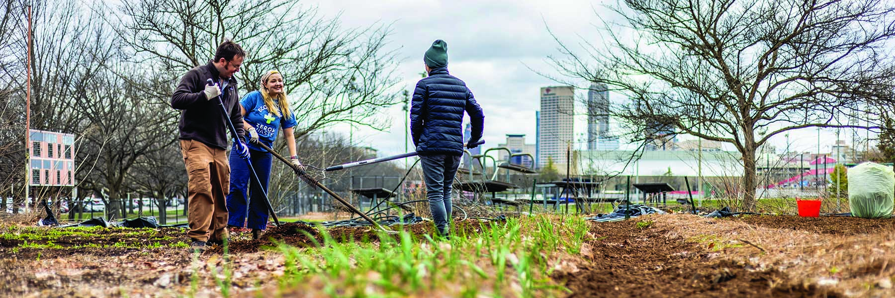 Students work in field with Indy skyline in back.